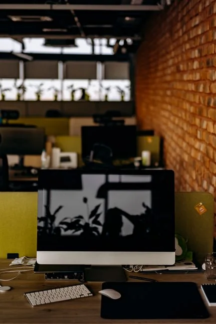 Un espace de travail contemporain avec deux écrans d’ordinateur affichant des projets de web design, mettant en avant la technologie et la productivité.